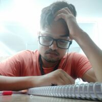 लाइब्रेरी के कौने में, एक लड़का उदास बैठा हैं